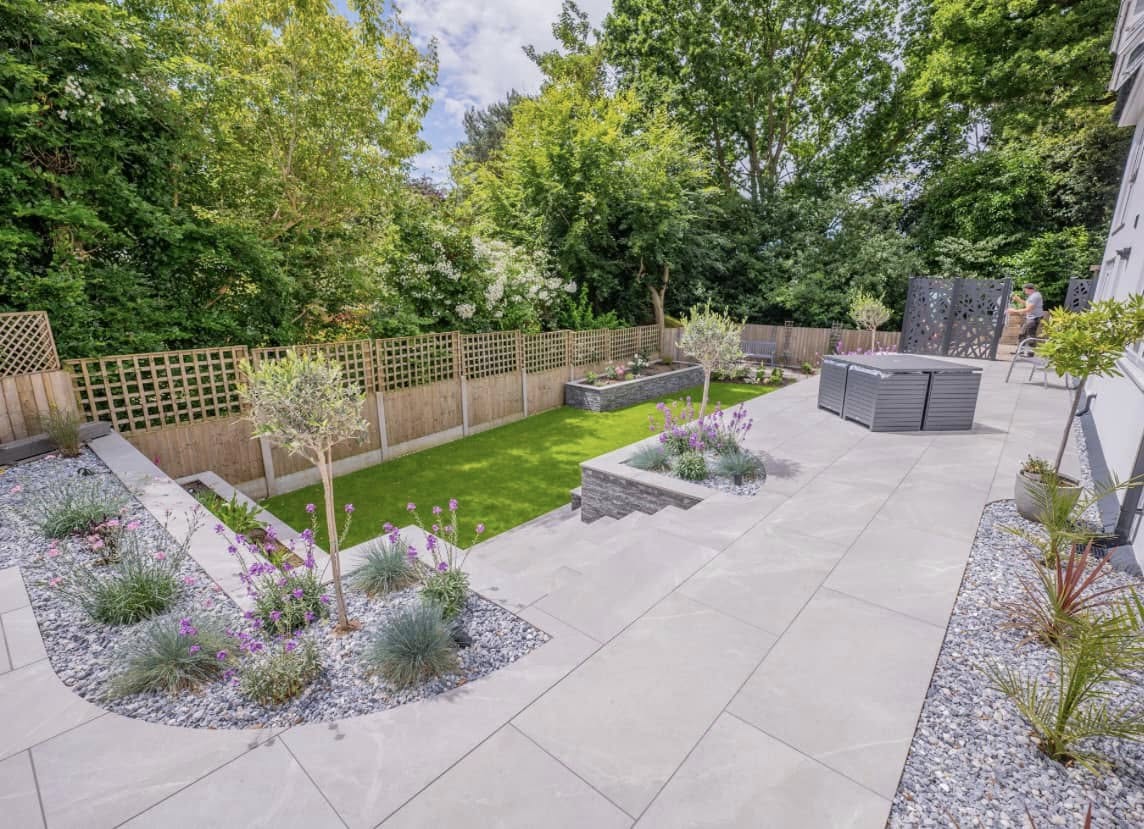 Full garden makeover with porcelain patio, olive trees and hot tub area by Glorious Gardens Son & Co.