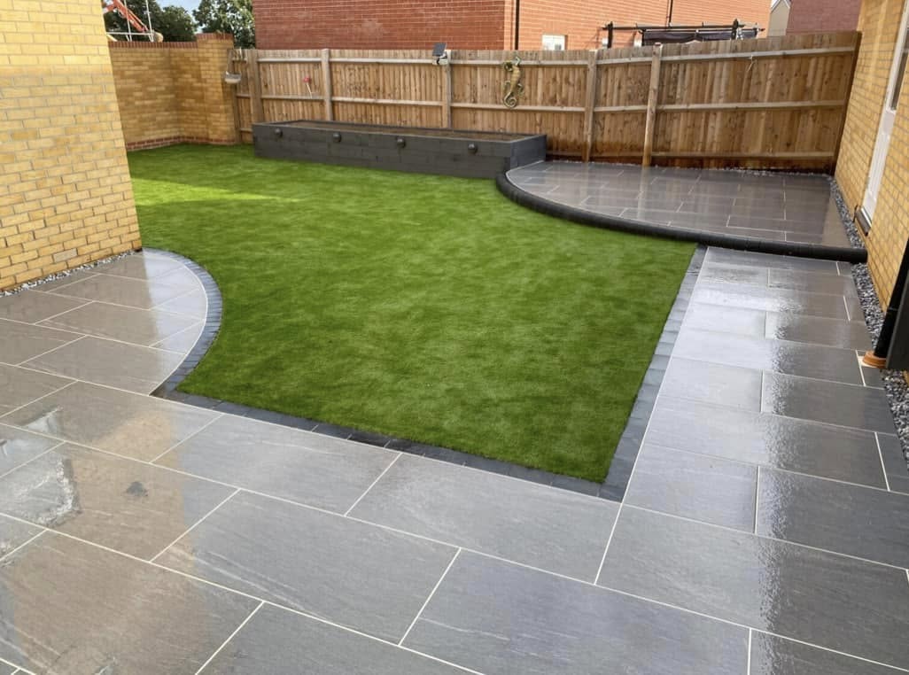 New build garden with slate paving and curved lawn edges by Glorious Gardens Son & Co.